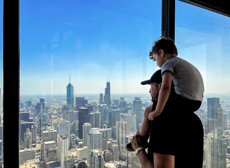 Family at 360 Chicago's south-facing windows looking at Willis Tower and the downtown skyline
