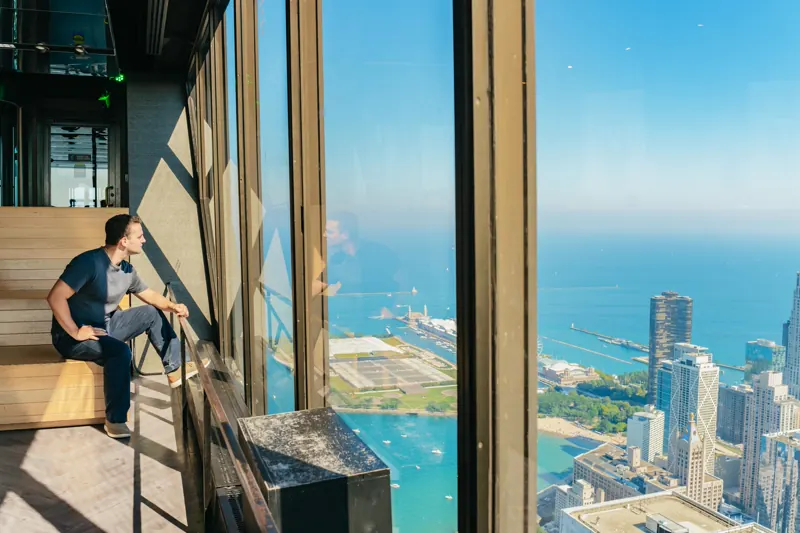 Visitor at 360 Chicago's east-facing window seat looking toward Lake Michigan and Navy Pier