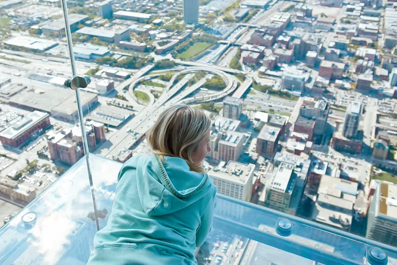 Visitor looking down through The Ledge glass floor at Chicago streets 1,353 feet below